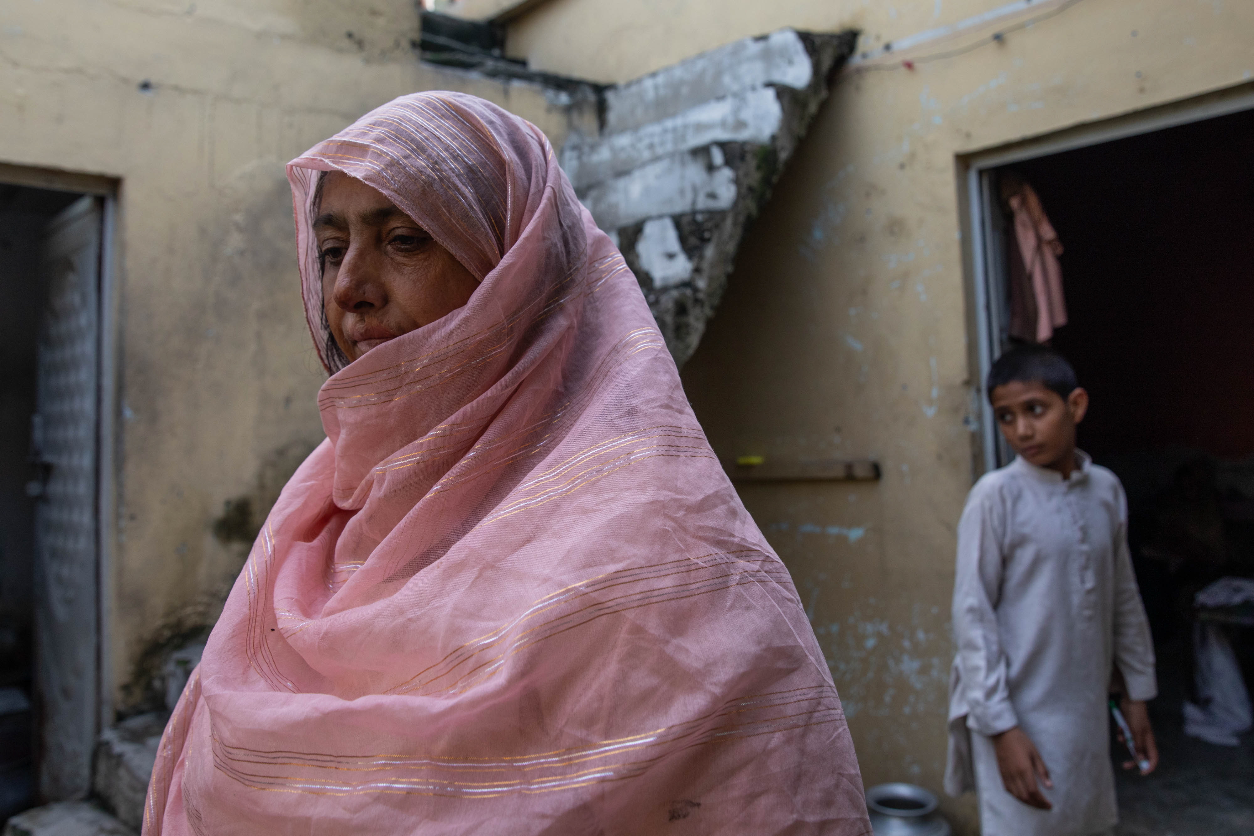 Saida Tanvir stands inside her partially damaged home near Bari Imam on August 20 in Islamabad, Pakistan. Her son, Azeem Ahmed, 16, died while trying to block a bulldozer from crushing their roadside grocery store over the winter.